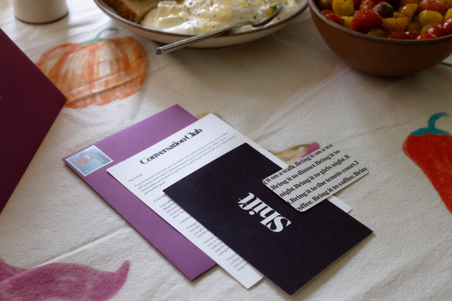 The Conversation Club letter and conversation cards on a table set for dinner