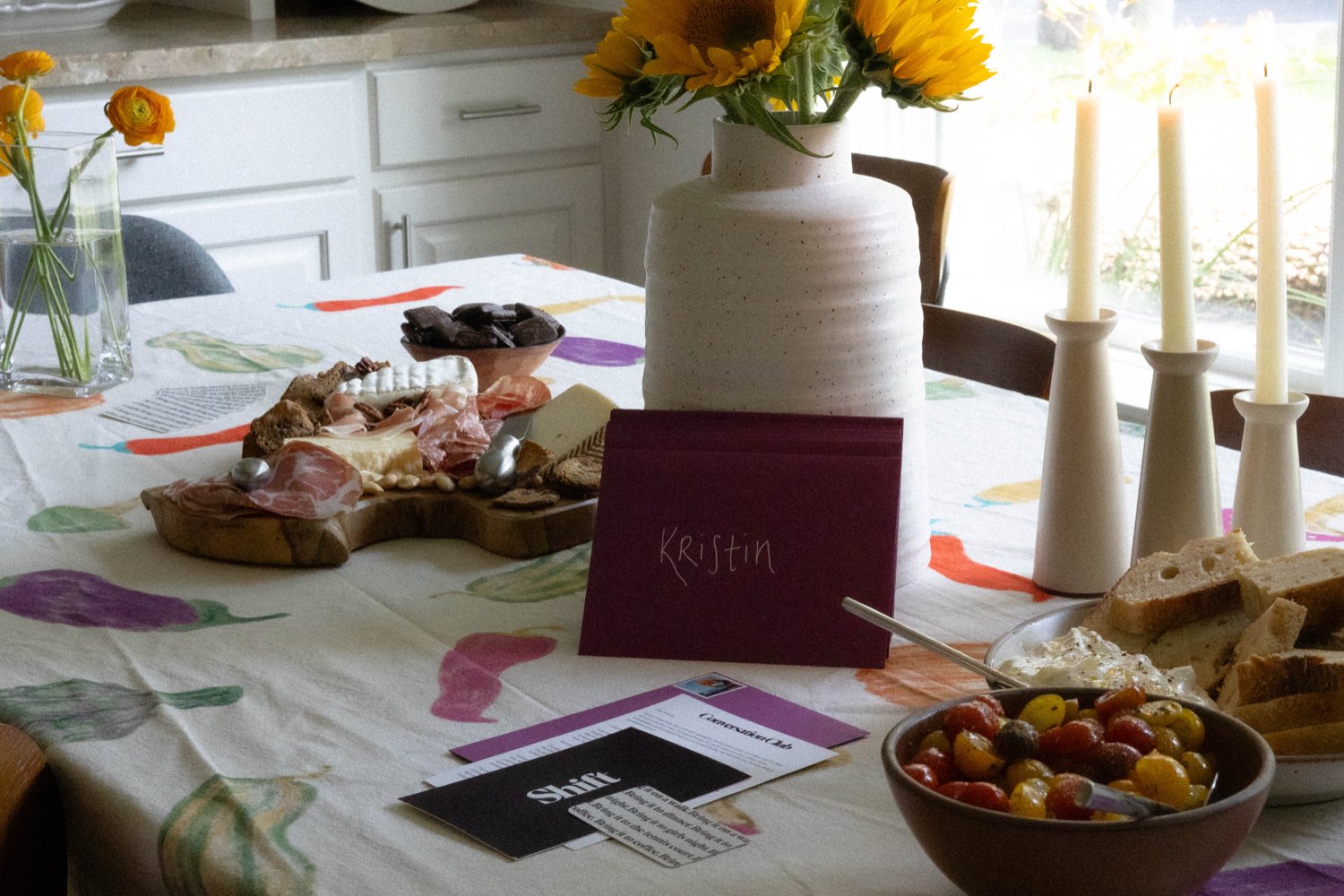 A dinner table set with place cards, candles, and a charcuterie board